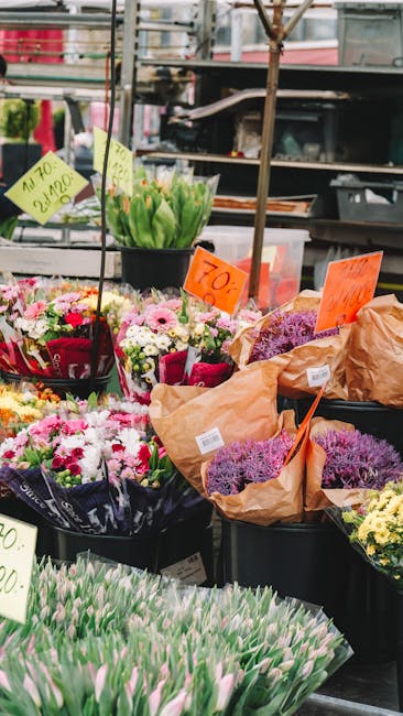 A display of fresh floral bouquets at an outdoor flower stall, featuring a variety of spring flowers including pink and white chrysanthemums, purple and pink tulips, and daffodils arranged in pots and